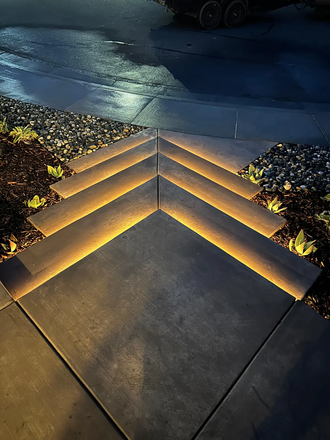 Commercial property with professional landscape lighting at night, dramatic dark atmosphere, warm golden illumination on building facade